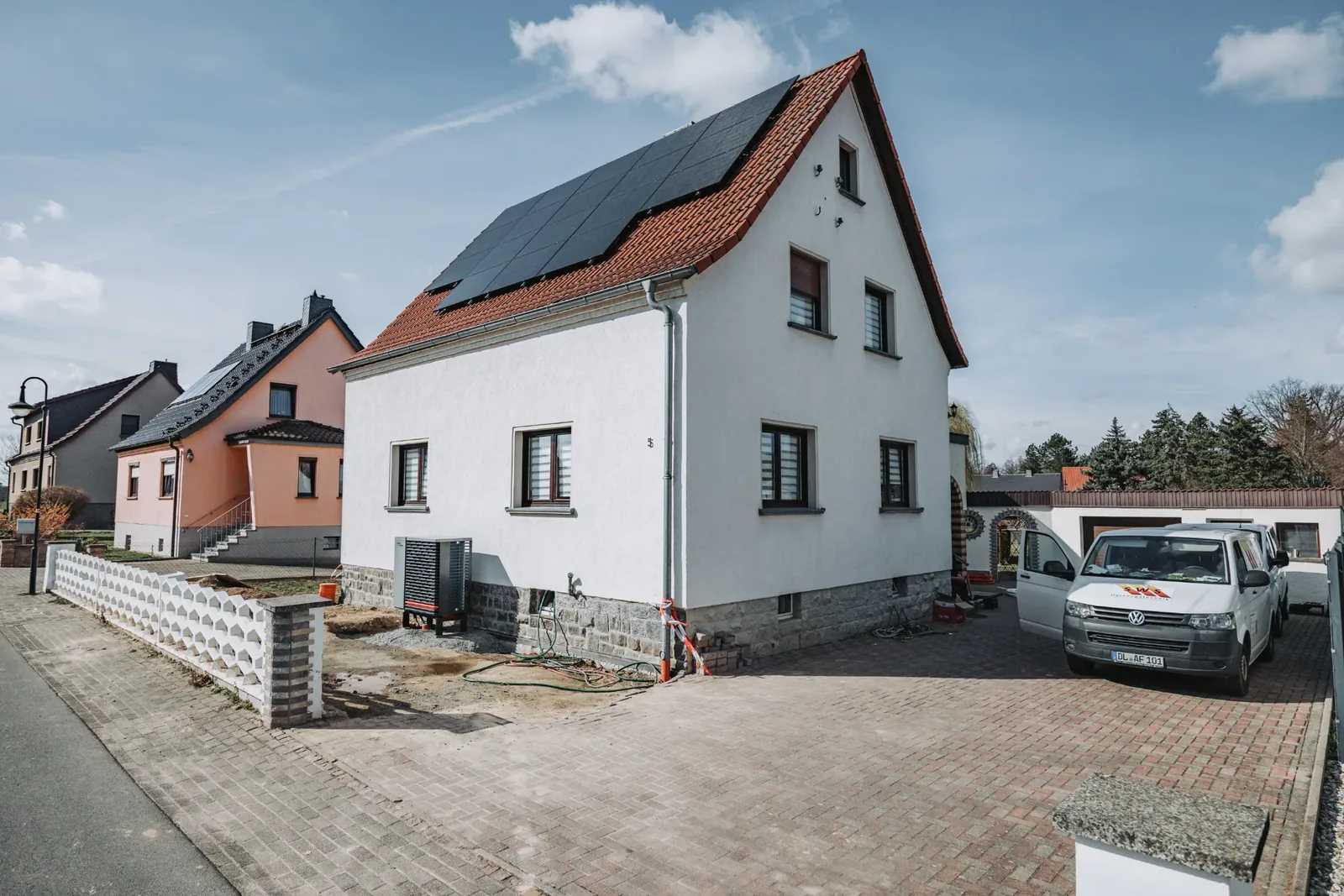 Einfamilienhaus mit Photovoltaik auf dem Dach und Wärmepumpe an der Hauswand.